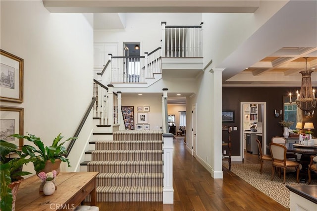 interior space with an inviting chandelier, ornamental molding, beamed ceiling, hardwood / wood-style floors, and coffered ceiling