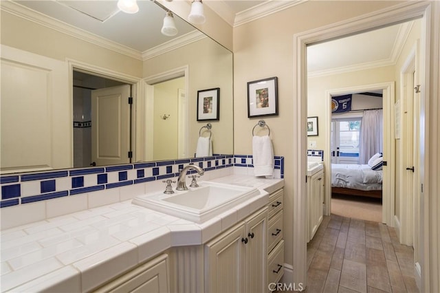 ensuite bathroom with decorative backsplash, wood-type flooring, ornamental molding, and vanity