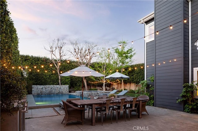 view of patio / terrace featuring a pool with connected hot tub, outdoor dining area, and fence