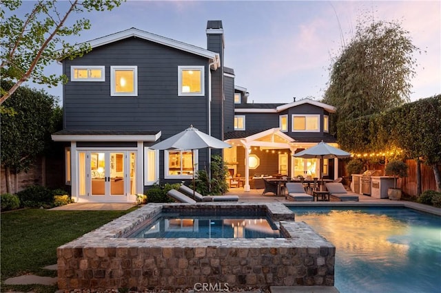 rear view of house featuring french doors, a fenced in pool, area for grilling, and a chimney