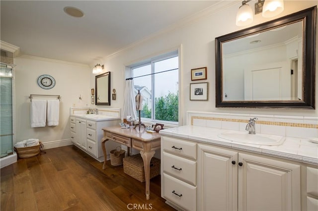 full bathroom featuring two vanities, a sink, ornamental molding, and wood finished floors