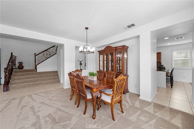 dining area with a notable chandelier, light tile patterned floors, visible vents, and light colored carpet