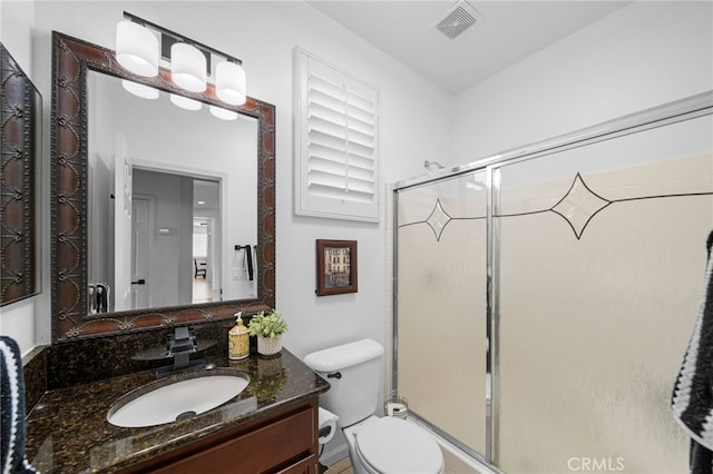full bathroom featuring toilet, vanity, visible vents, and a stall shower