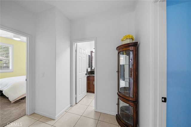 corridor with baseboards and light tile patterned flooring