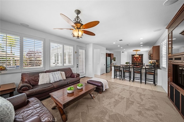 living area featuring light carpet, light tile patterned flooring, a ceiling fan, and plenty of natural light