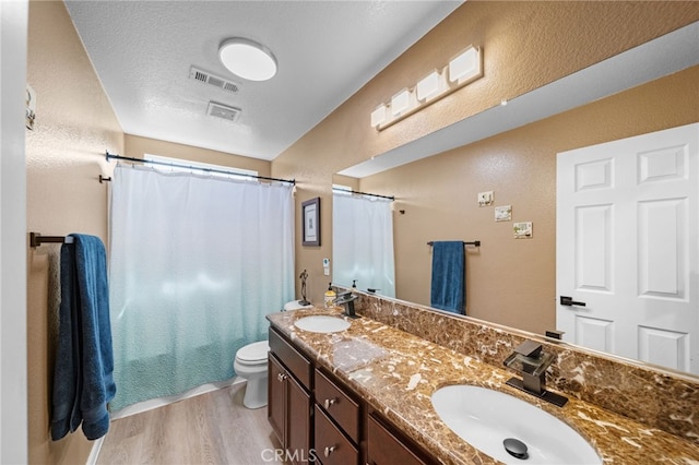 bathroom with visible vents, a sink, toilet, and wood finished floors