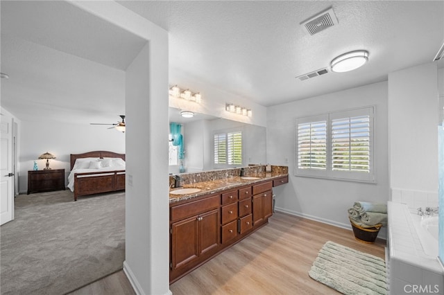 bathroom featuring wood finished floors, ceiling fan, a sink, and visible vents