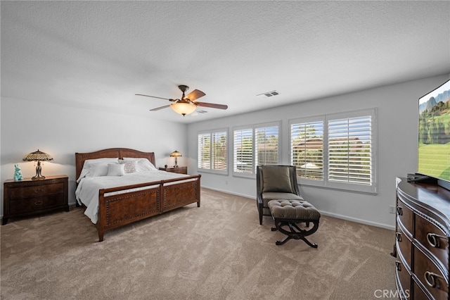 bedroom with visible vents, light colored carpet, a textured ceiling, and ceiling fan