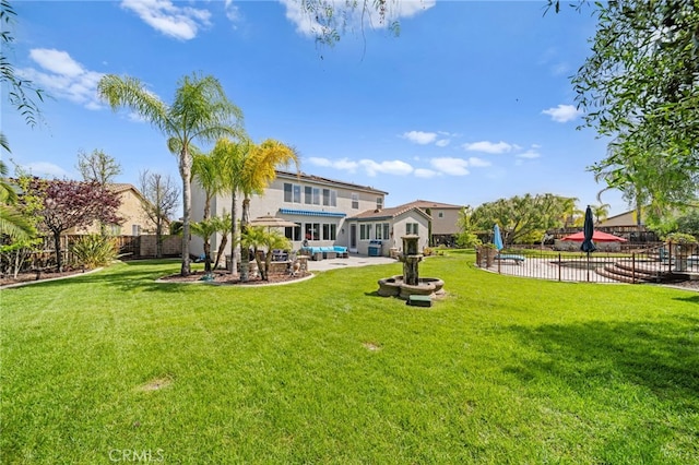 back of property with a patio, a fenced backyard, stucco siding, and a lawn