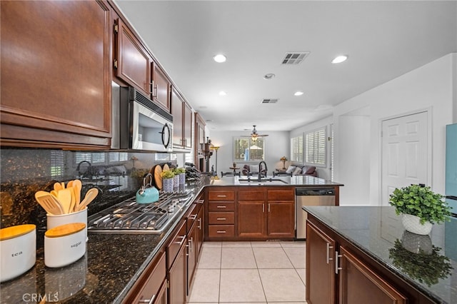 kitchen with a peninsula, appliances with stainless steel finishes, a sink, and visible vents