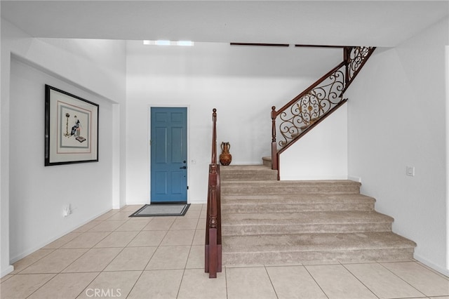 foyer entrance featuring stairway, baseboards, and light tile patterned flooring