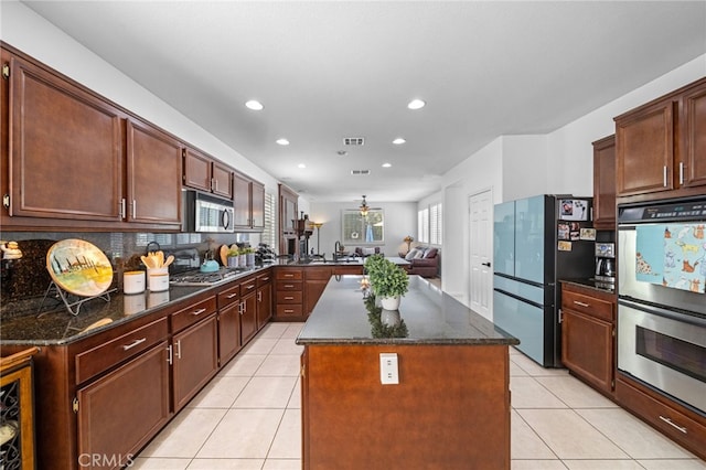 kitchen with tasteful backsplash, light tile patterned floors, appliances with stainless steel finishes, recessed lighting, and a kitchen island