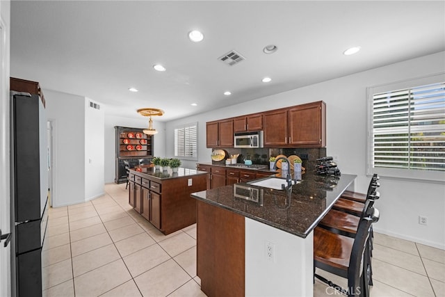 kitchen featuring stainless steel microwave, plenty of natural light, visible vents, and freestanding refrigerator