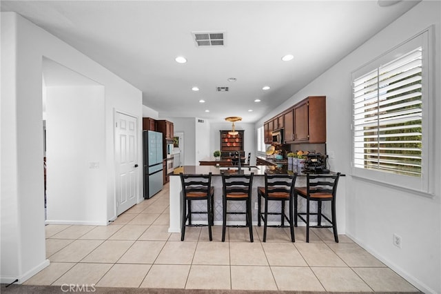 kitchen featuring light tile patterned floors, dark countertops, appliances with stainless steel finishes, a peninsula, and recessed lighting