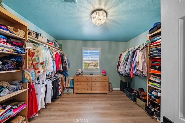 spacious closet with a chandelier, visible vents, and wood finished floors