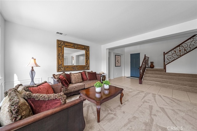 living area featuring light tile patterned flooring, visible vents, and stairway