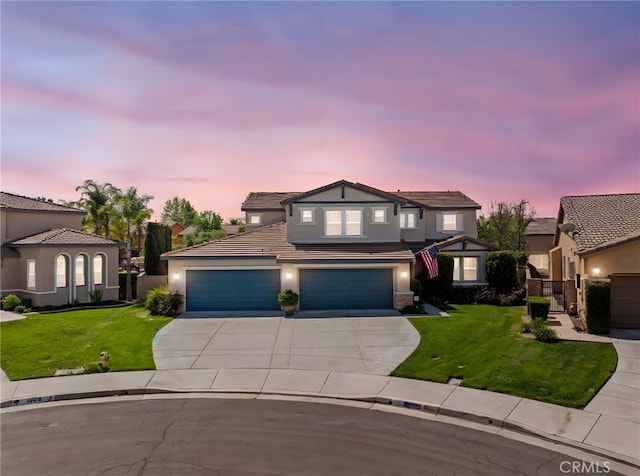 traditional home with a tile roof, a lawn, driveway, and stucco siding