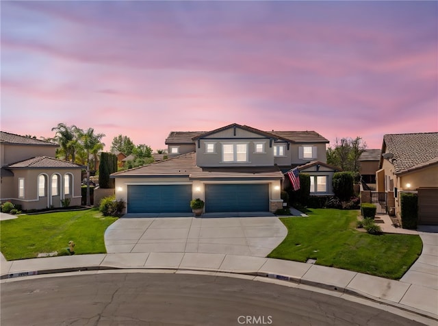 traditional-style home featuring a tiled roof, a front lawn, driveway, and stucco siding