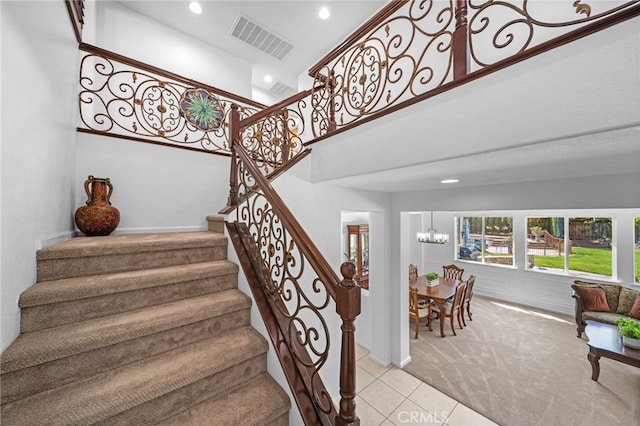 stairs with an inviting chandelier, tile patterned flooring, visible vents, carpet floors, and recessed lighting
