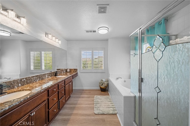 bathroom with a sink, visible vents, wood finished floors, and a garden tub