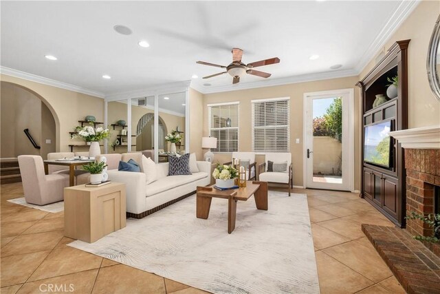 115 Vermillion, Irvine, CA 92603 - living room featuring crown molding, arched walkways, a ceiling fan, light tile patterned flooring, and a brick fireplace
