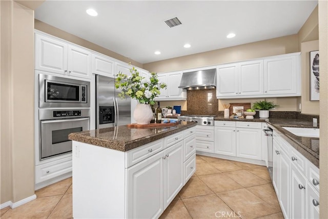 115 Vermillion, Irvine, CA 92603 - kitchen with light tile patterned floors, visible vents, wall chimney exhaust hood, built in appliances, and a kitchen island