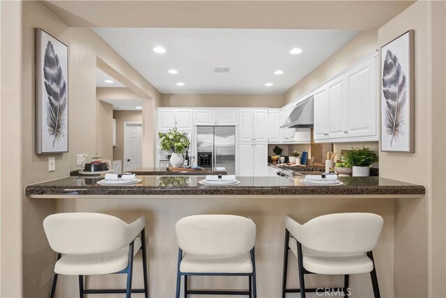 115 Vermillion, Irvine, CA 92603 - kitchen featuring a peninsula, dark stone counters, range hood, and stainless steel built in fridge