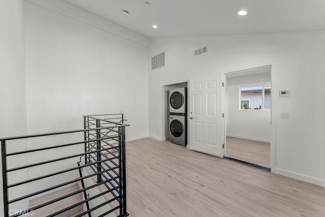 washroom featuring visible vents, light wood-style flooring, stacked washing maching and dryer, and laundry area
