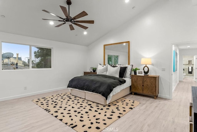 bedroom with high vaulted ceiling, light wood-style floors, and baseboards