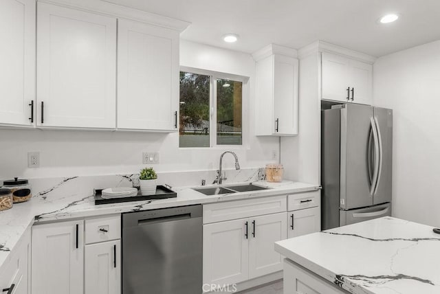 kitchen with light stone counters, recessed lighting, white cabinetry, appliances with stainless steel finishes, and a sink