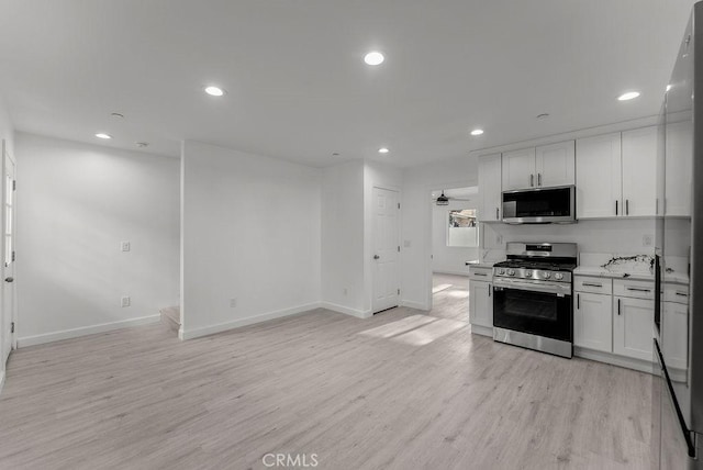 kitchen featuring light wood-style floors, appliances with stainless steel finishes, baseboards, and white cabinetry