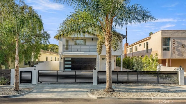 view of front of property featuring a fenced front yard, stucco siding, a balcony, an attached garage, and concrete driveway
