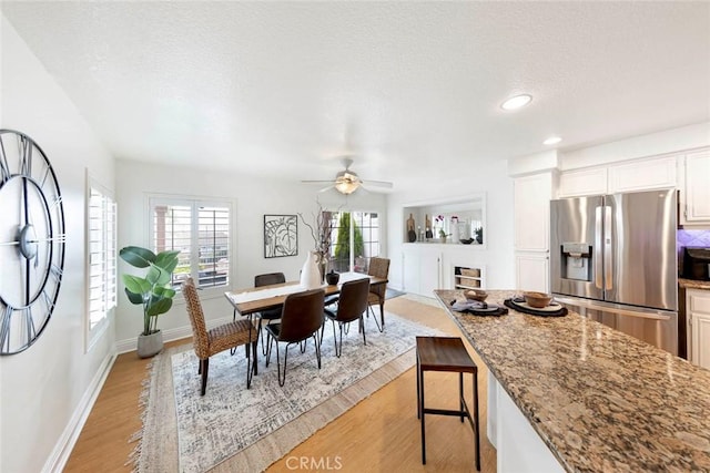dining area with light wood-style flooring, a textured ceiling, baseboards, recessed lighting, and a ceiling fan