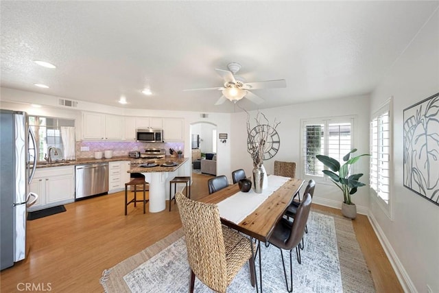 dining area featuring plenty of natural light, a ceiling fan, visible vents, and light wood-style floors