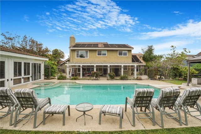 view of swimming pool featuring fence and a pool with connected hot tub