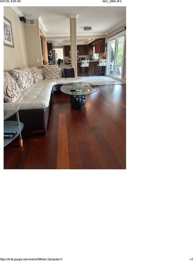 living area featuring visible vents, wood finished floors, ornamental molding, and decorative columns