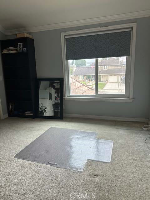 unfurnished living room featuring ornamental molding, carpet, and baseboards