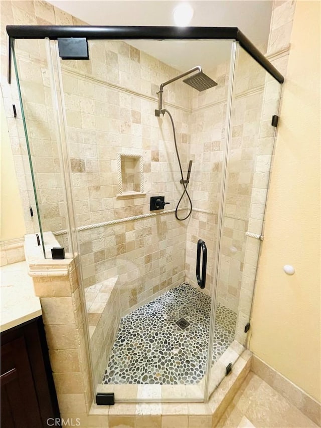 full bath featuring a stall shower, vanity, baseboards, and tile patterned floors