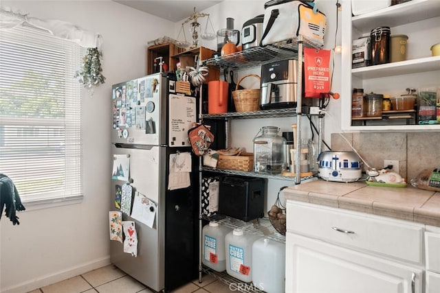 1109 Ivy St, Chico, CA 95928 - kitchen with open shelves, freestanding refrigerator, white cabinetry, tile countertops, and light tile patterned flooring