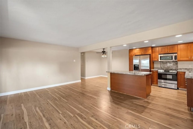 659 Avenida Sevilla Unit D, Laguna Woods, CA 92637 - kitchen with appliances with stainless steel finishes, baseboards, light wood-type flooring, and brown cabinets