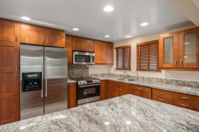 659 Avenida Sevilla Unit D, Laguna Woods, CA 92637 - kitchen featuring light stone countertops, brown cabinets, a sink, glass insert cabinets, and stainless steel appliances