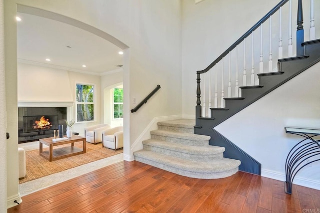1664 Aryana Dr, Encinitas, CA 92024 - stairs featuring hardwood / wood-style flooring, arched walkways, crown molding, a glass covered fireplace, and recessed lighting