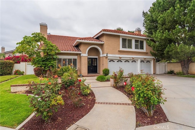mediterranean / spanish house featuring fence, stucco siding, a chimney, and a garage