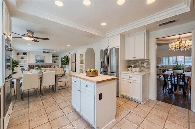 kitchen with stainless steel fridge, wood counters, open floor plan, visible vents, and ceiling fan with notable chandelier