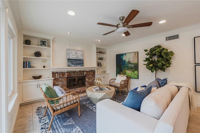 living area with ornamental molding, light tile patterned floors, a ceiling fan, visible vents, and built in shelves