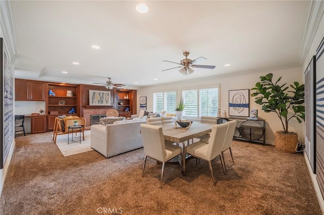 dining area featuring a brick fireplace, ornamental molding, a ceiling fan, carpet floors, and recessed lighting