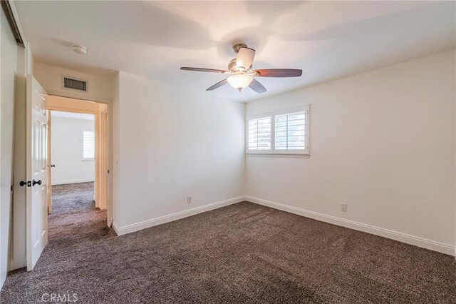spare room featuring carpet flooring, visible vents, baseboards, and ceiling fan