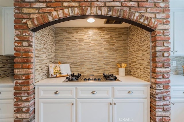 bar featuring decorative backsplash, arched walkways, and stainless steel gas stovetop