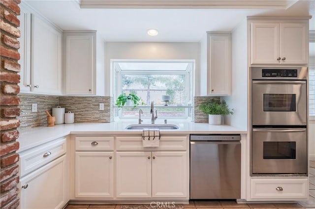 kitchen with light countertops, decorative backsplash, a sink, and stainless steel appliances