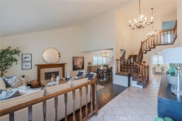 living area featuring a chandelier, high vaulted ceiling, a wealth of natural light, and stairs